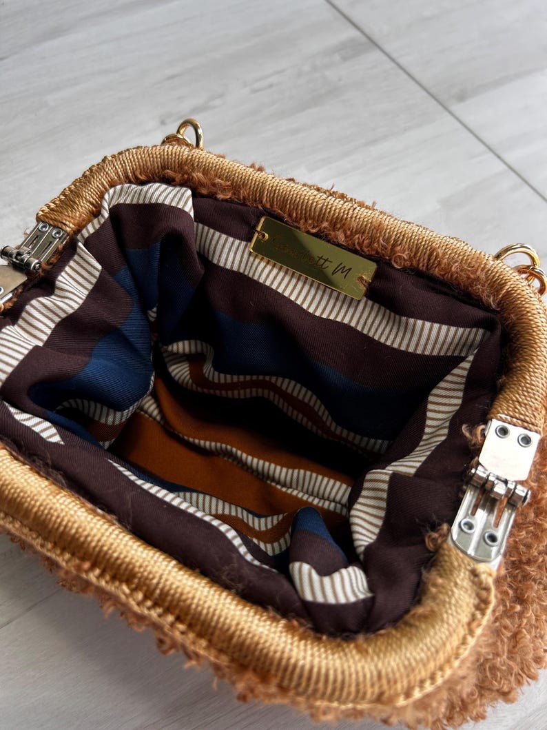 Open brown handbag showing striped lining and clasp