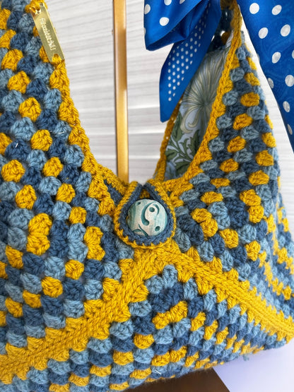 Side view of the granny-square crochet bag with wood handles