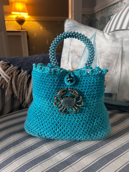 Turquoise crochet bag with beaded handle and gold crab detail