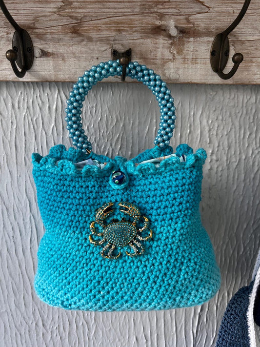 Turquoise crochet handbag with beaded handle and crab embellishment