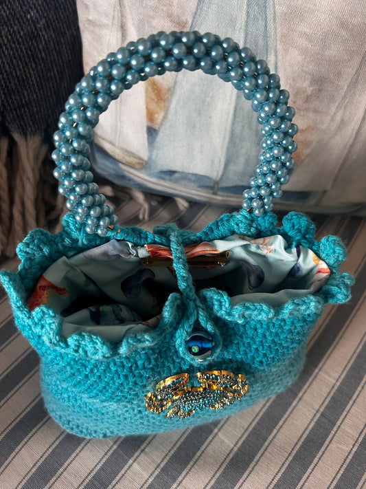 Turquoise crochet bag with beaded handle and patterned lining