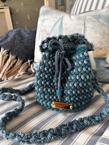 Teal and blue crochet drawstring bag with braided strap and beaded ends