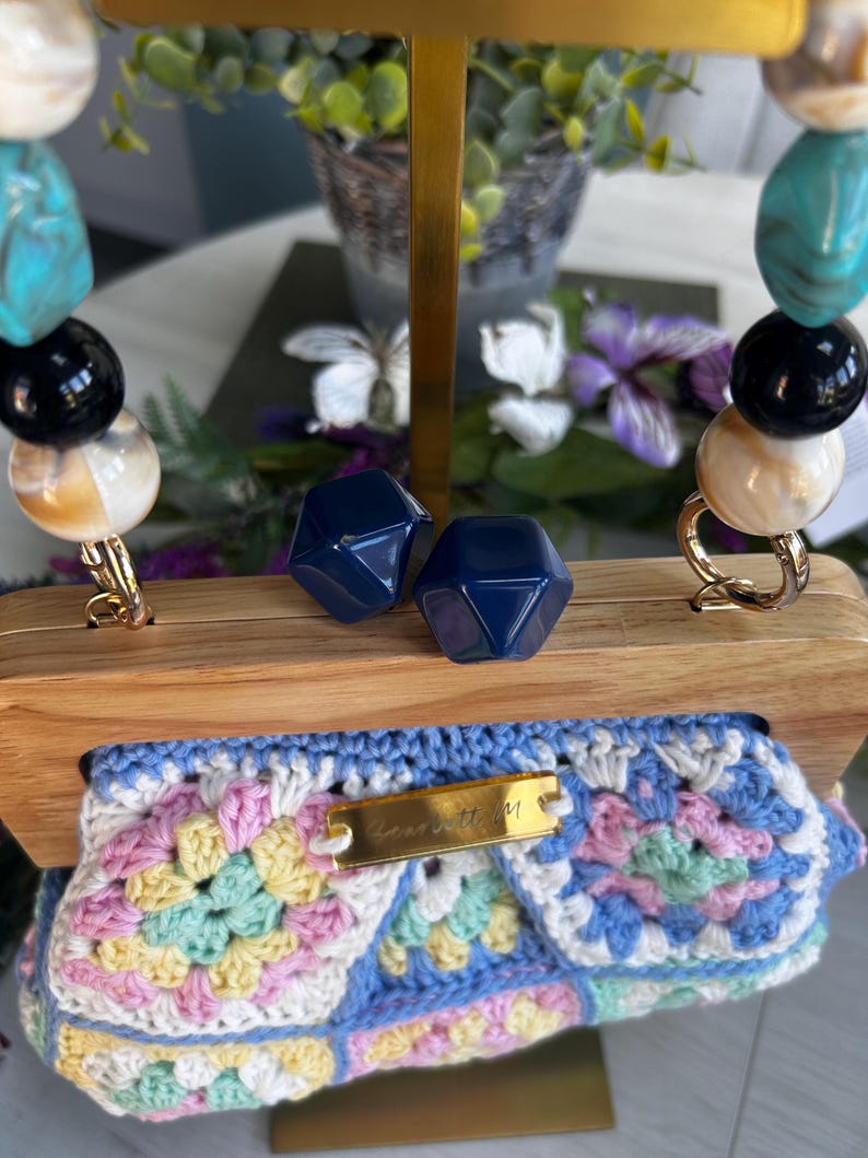 Pastel crochet clutch with matching earrings on wooden frame