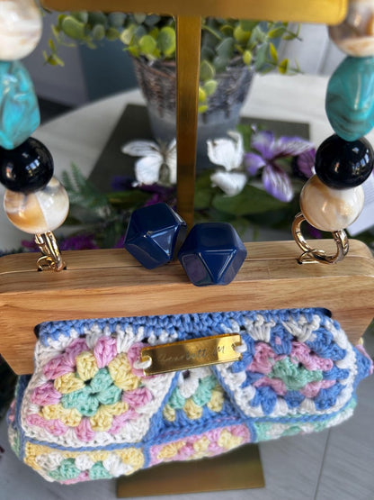 Pastel crochet clutch with matching earrings on wooden frame