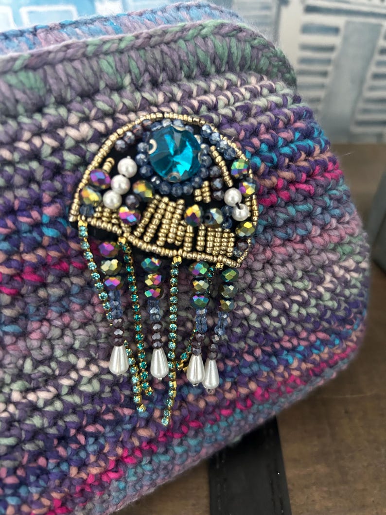Ocean-inspired crochet bag with teal jewel-encrusted brooch