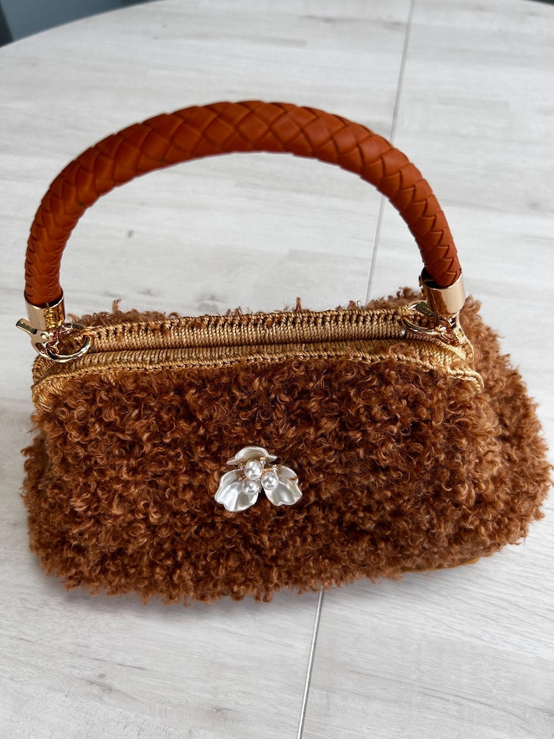 Fluffy brown handbag with braided handle and floral brooch