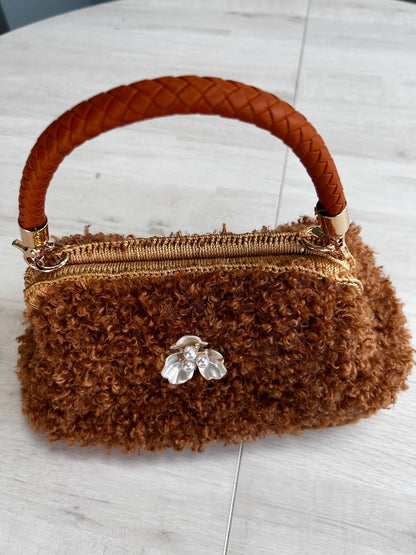 Fluffy brown handbag with braided handle and floral brooch
