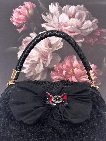 Black textured handbag with bow and crystal brooch
