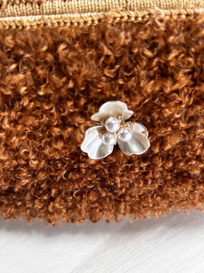 Close-up of white pearl flower brooch on brown bag