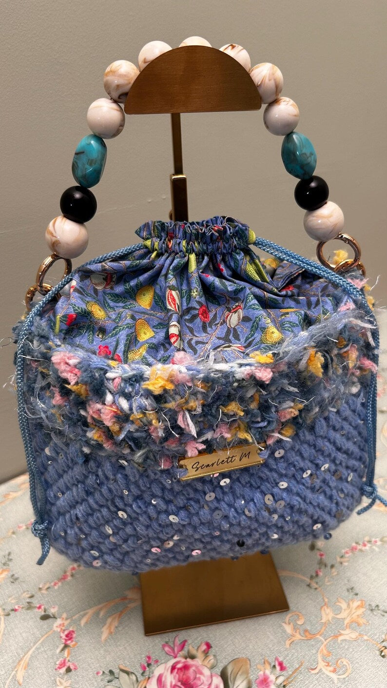 Blue crochet drawstring bag with sequins, floral top and beaded handle