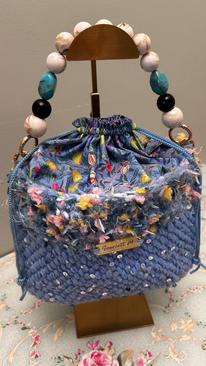 Blue crochet drawstring bag with sequins, floral top and beaded handle