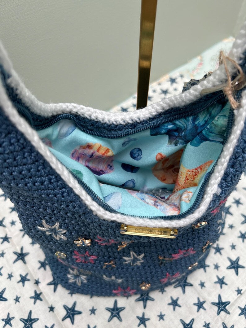 Blue crochet bag with seashell-print lining and zip closure