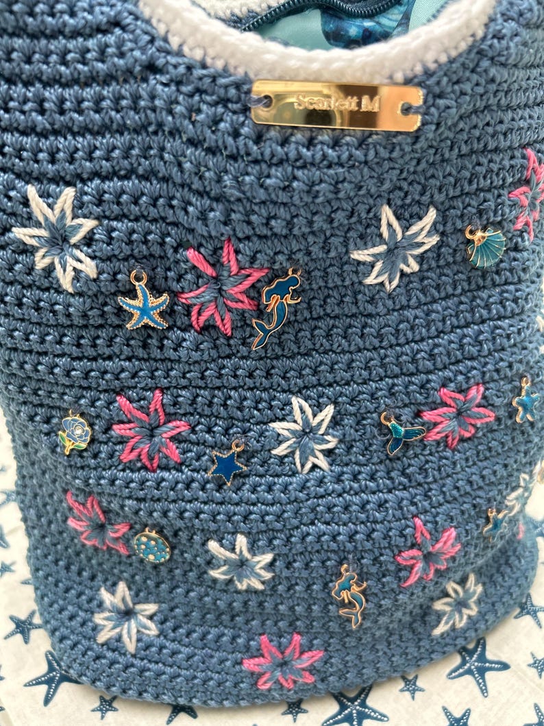 Blue crochet bucket bag with embroidered flowers and charms