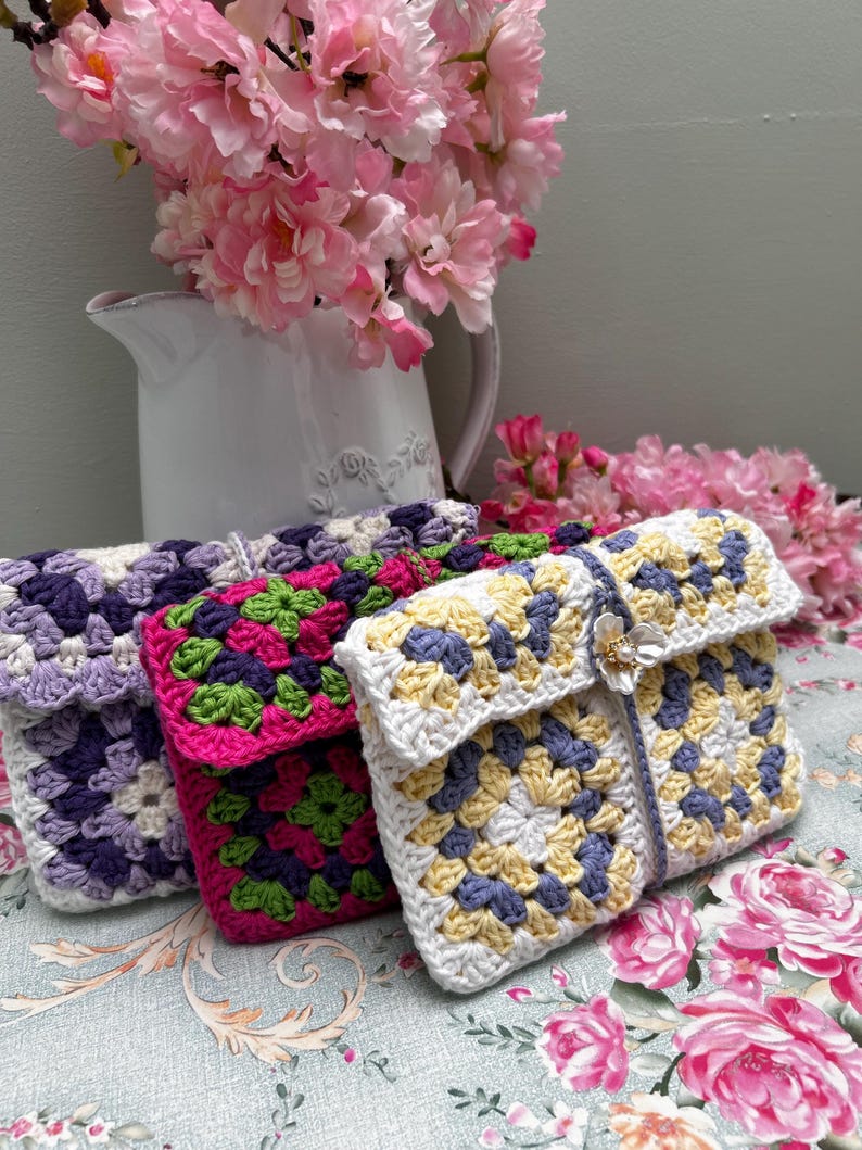 Three floral granny square crochet pouches in assorted colours